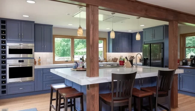 Cooper-Township-Kitchen-with-Island-aspect-ratio-1920-1100 Custom kitchen with blue cabinetry, large white island, wood support posts, pendant lighting, bar seating, and stainless steel appliances