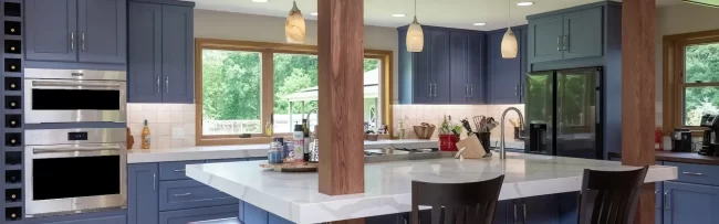 Cooper Township Kitchen with Island | Pennings & Sons Custom kitchen with blue cabinetry, large white island, wood support posts, pendant lighting, bar seating, and stainless steel appliances