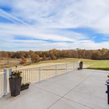 Spacious backyard deck on a Galesburg custom home with white railing, outdoor seating and open countryside views.