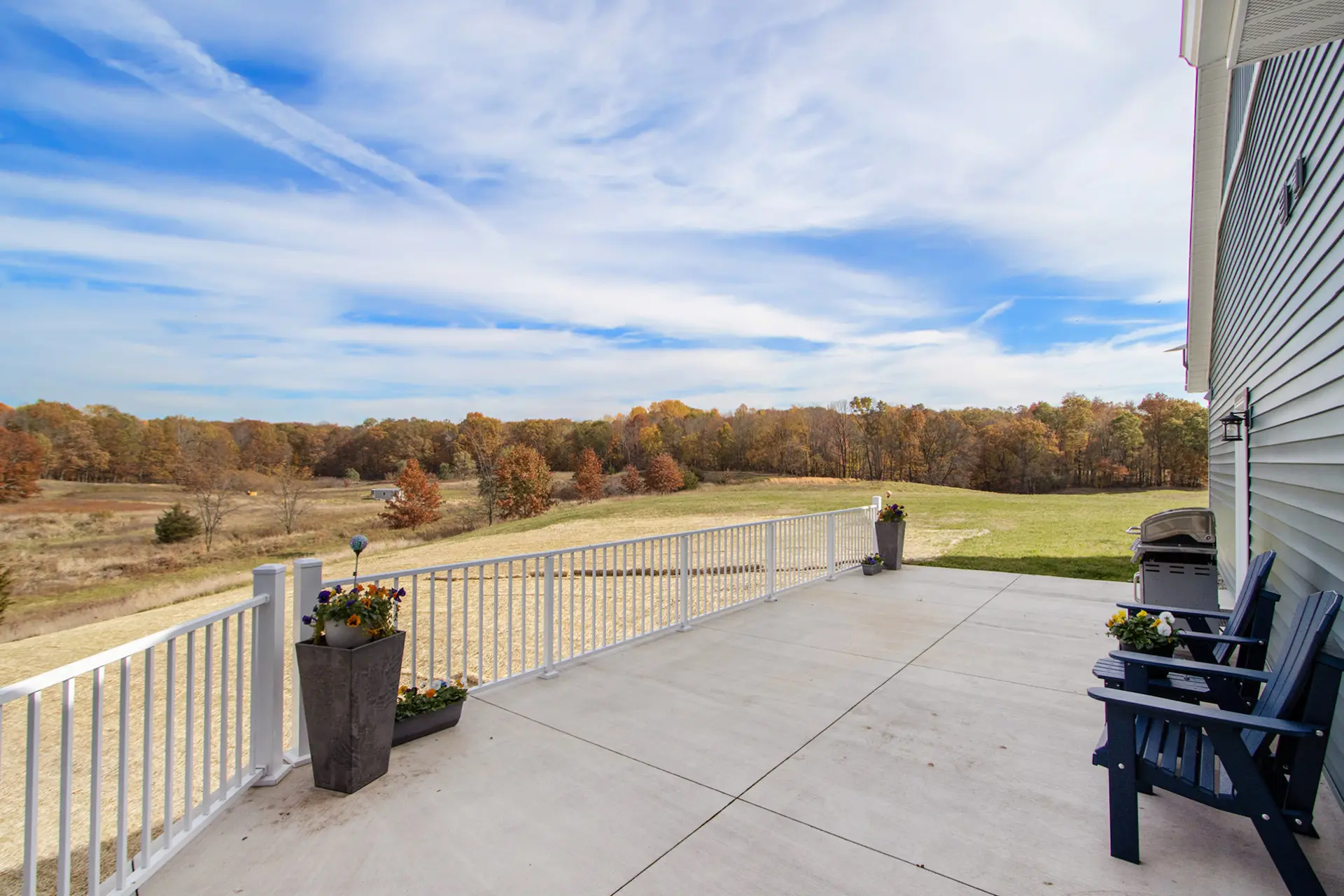 Spacious backyard deck on a Galesburg custom home with white railing, outdoor seating and open countryside views.