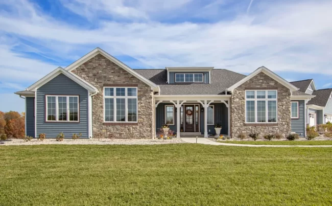Galesburg Custom Home Front Exterior | Pennings & Sons Front exterior of a Galesburg custom home with blue siding, stone accents, large windows and covered entry.