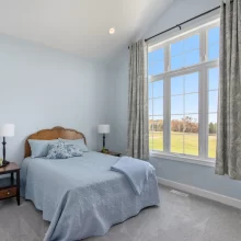 Guest bedroom in a Galesburg custom home with blue bedding, vaulted ceiling, large windows and countryside views.