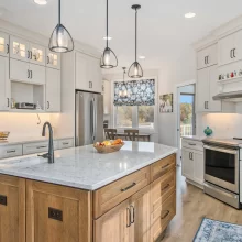 Custom kitchen in a Galesburg home with a wood island, white cabinetry, pendant lights, stainless appliances and floral window shade.