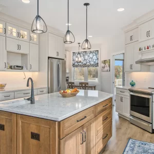 Custom kitchen in a Galesburg home with a wood island, white cabinetry, pendant lights, stainless appliances and floral window shade.