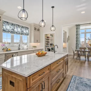 Bright Galesburg custom kitchen with wood island, marble-style countertops, walk-in pantry and view into the dining room.