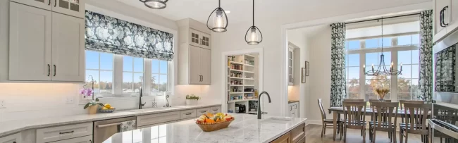 Bright Galesburg custom kitchen with wood island, marble-style countertops, walk-in pantry and view into the dining room.