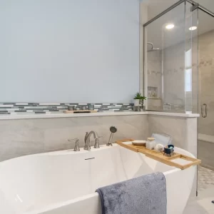Primary bathroom with freestanding soaking tub, glass tile shower.