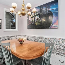 Breakfast nook with built-in floral banquette, wood dining table, statement chandelier, artwork, and lake-inspired décor