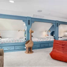 Custom built-in bunk beds with blue trim, white shiplap walls, and cozy children’s sleeping spaces