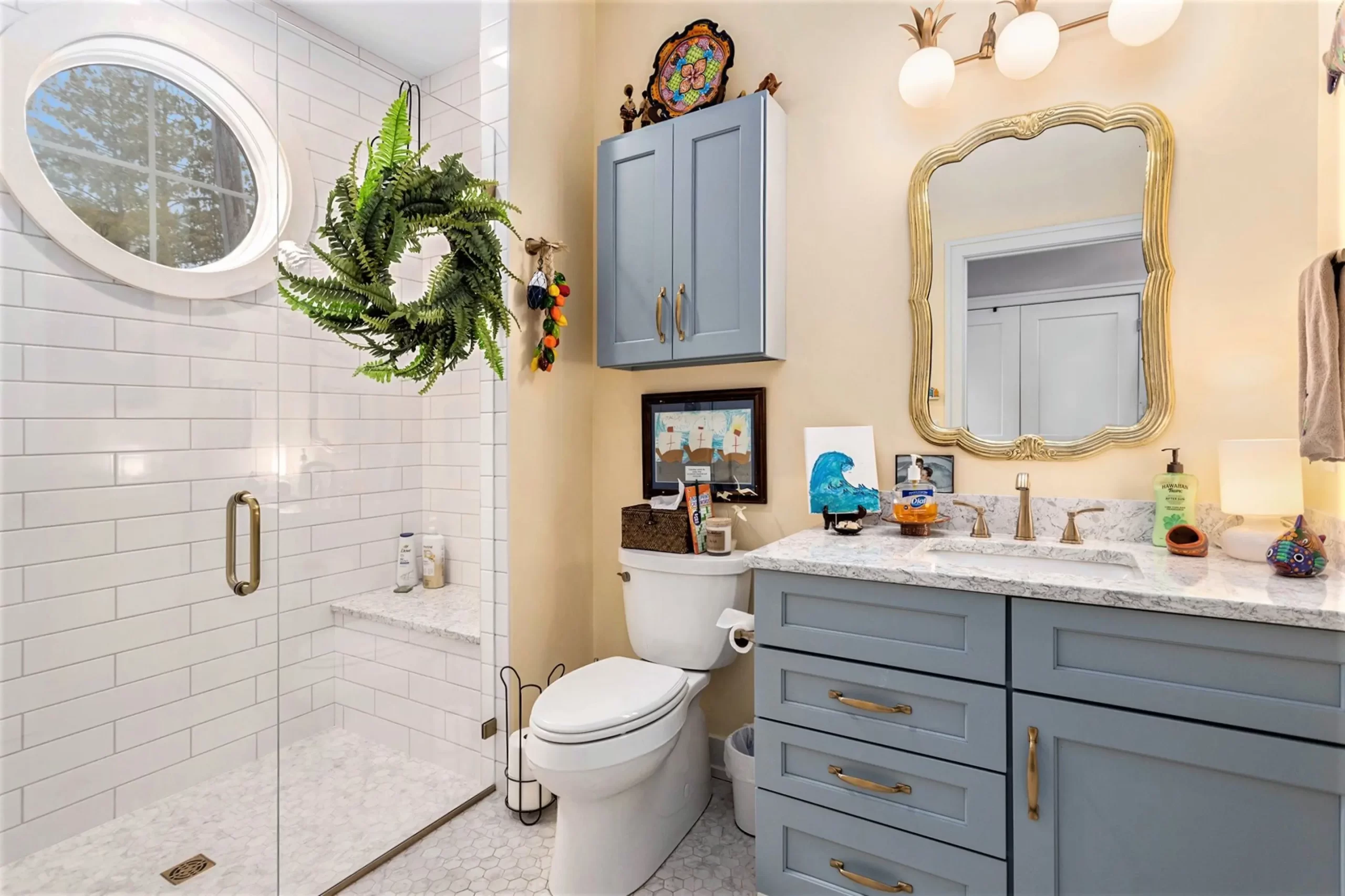 Guest bathroom with blue vanity, gold mirror, marble countertop, white subway tile walk-in shower, and glass door