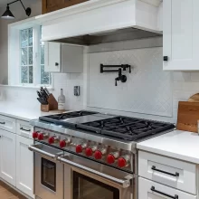 Wolf Range with red knobs and a black pot filler
