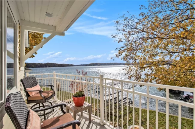 Lake View Balcony with Outdoor Seating | Pennings & Sons Covered balcony with outdoor seating overlooking the lake, docks, and colorful autumn trees