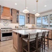 Custom kitchen with large island, copper range hood, paneled cabinetry, pendant lights, and lake views through wide windows