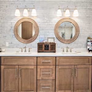 Double vanity with custom wood cabinetry, polished fixtures, two round mirrors, bright lighting, and tile backsplash