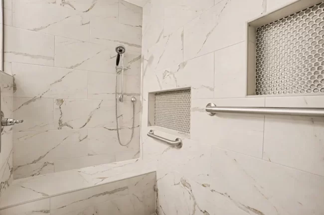 Accessible Shower with Grab Bars and Niches | Pennings & Sons Accessible tile shower with grab bars, recessed storage niches, handheld shower head, and built-in bench