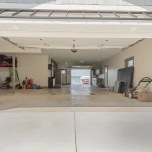 Open garage bay showing a finished drive-through garage with concrete floor, storage areas, and a view through to Austin Lake