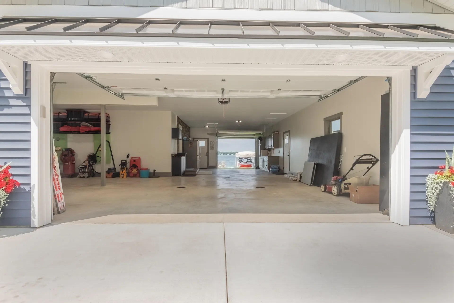 Open garage bay showing a finished drive-through garage with concrete floor, storage areas, and a view through to Austin Lake