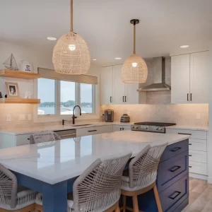 Custom kitchen with blue island, white cabinetry, woven pendant lights, lake-facing windows, tile backsplash, and open shelving