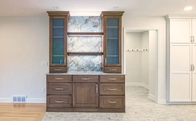 Built-In Dry Bar Cabinet | Pennings & Sons Floor to ceiling darker wood cabinet with marble backing attached to the wall in between living room and kitchen to be used as a dry bar