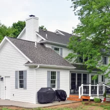 New garage addition extending out from the house facing North showing half size overhead door with side service door and two windows with gray shutters