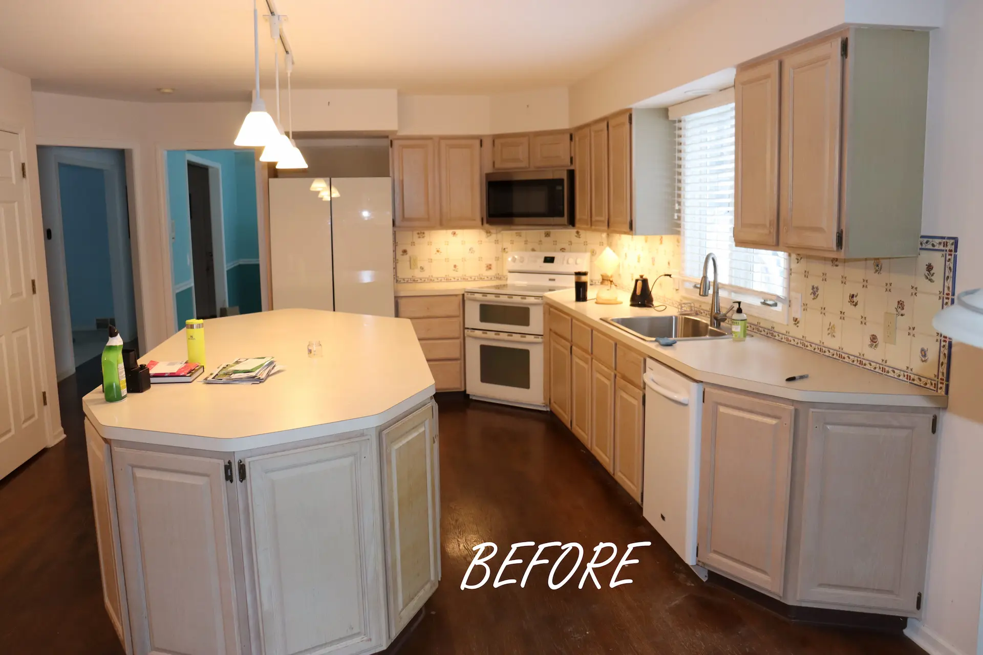 Kitchen with dark wood flooring and worn light brown cabinets and dated appliances
