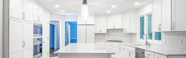 Kitchen with all white cabinets and island in the middle with matching brick shaped backsplash and flooring