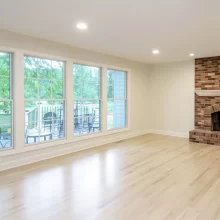 Updated living room with new lvp wood flooring, white paint and floor to ceiling windows that line the left side of the image facing the backyard