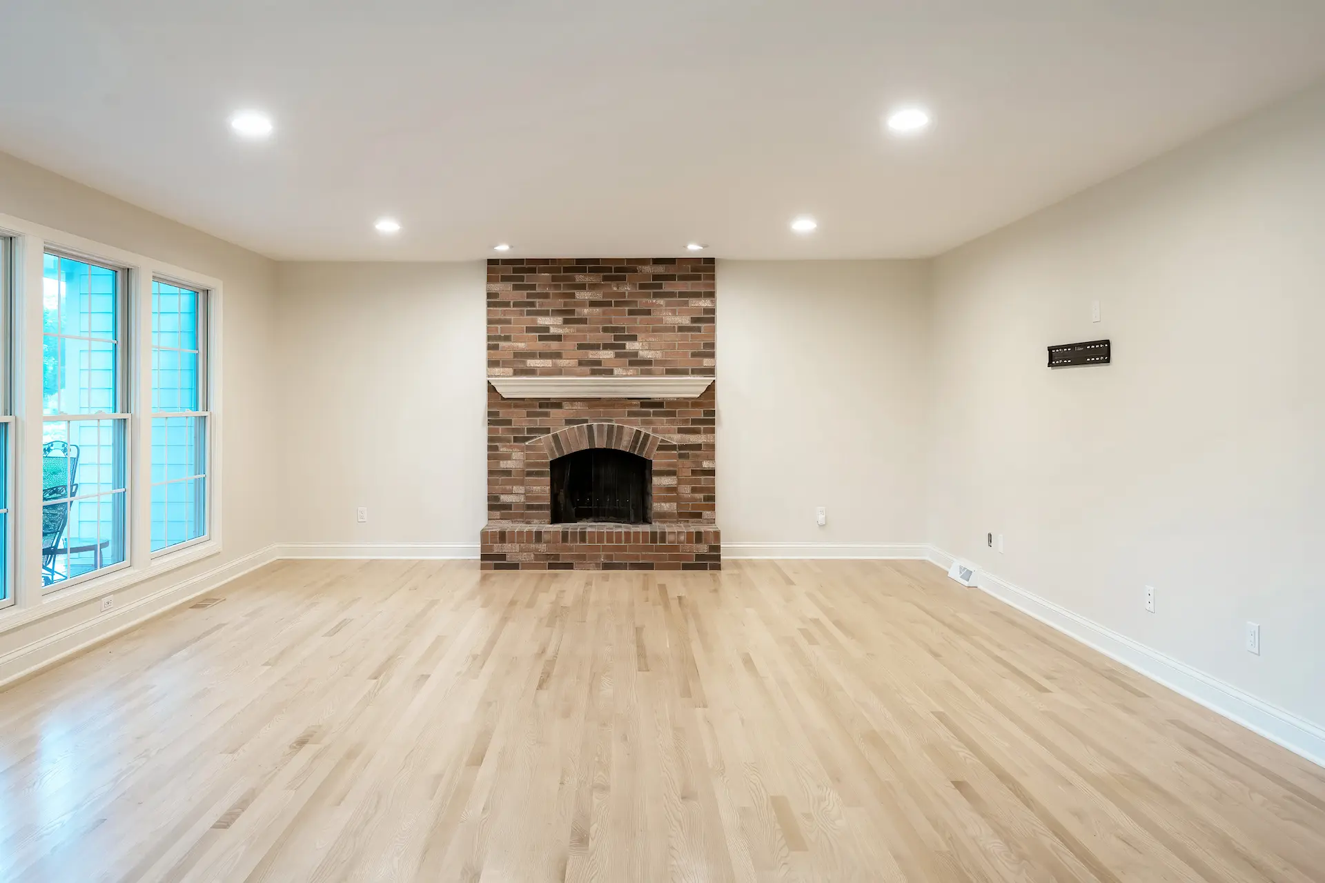 Updated living room with new lvp wood flooring, white paint and floor to ceiling windows that line the left side of the image facing the backyard