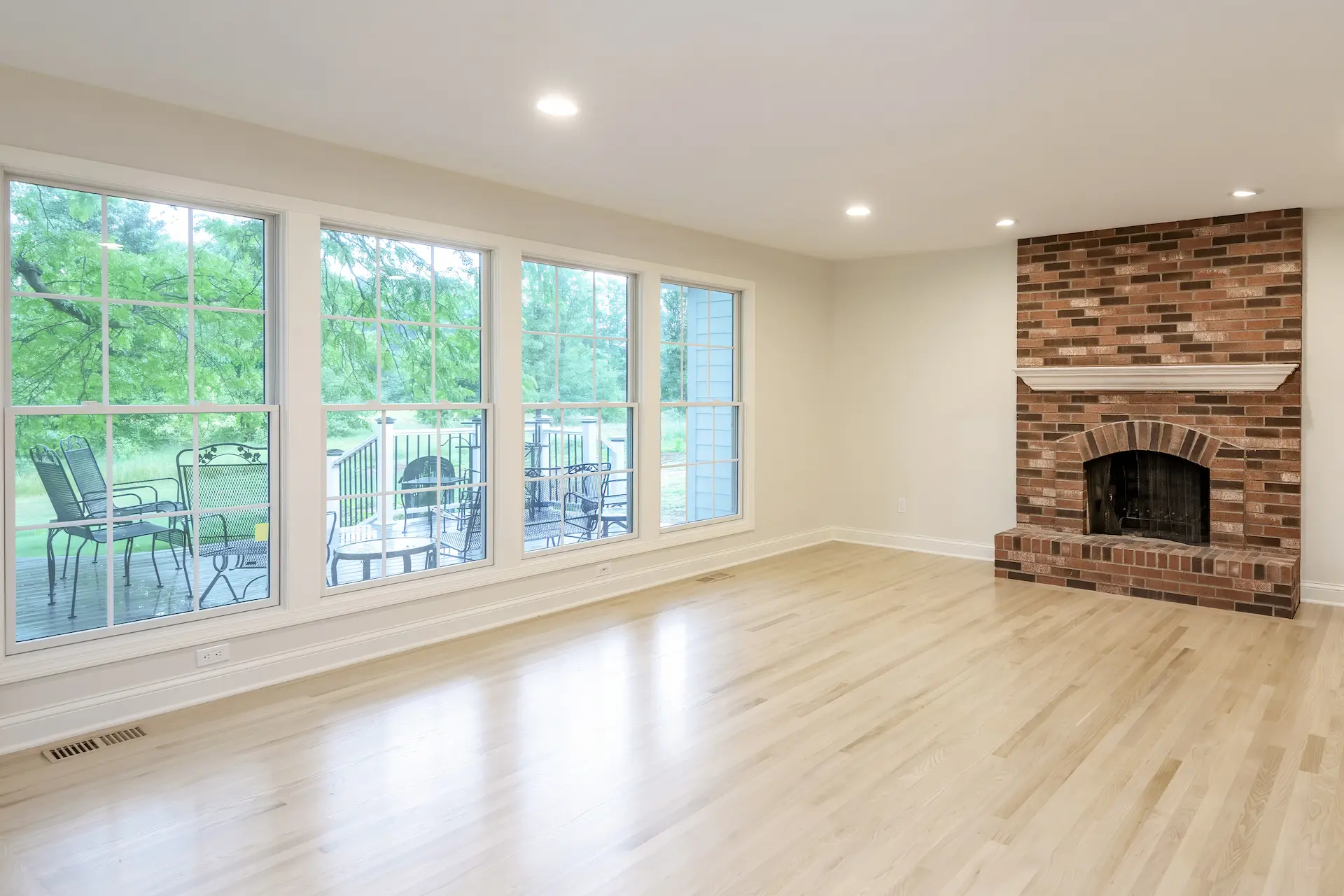 Updated living room with new lvp wood flooring, white paint and floor to ceiling windows that line the left side of the image facing the backyard