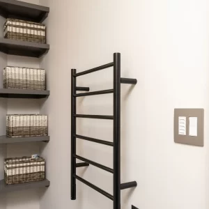 Bathroom storage area with black towel warmer, open shelves, woven baskets, gray tile floor, and wall controls