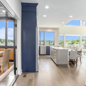 Open interior view showing kitchen, dining area, screened porch, large windows, and lake views.