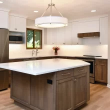 Custom kitchen with wood island, white upper cabinets, wood lower cabinets, quartz countertops, stainless steel appliances, and pendant light