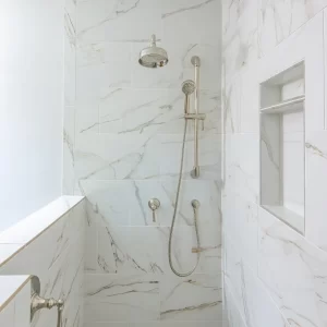 Walk-in shower with marble-look wall tile, built-in shower niche, handheld shower head, rain shower fixture, and white tile floor