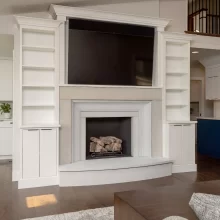 White custom fireplace built-ins with TV niche, open shelving, and living room cabinetry