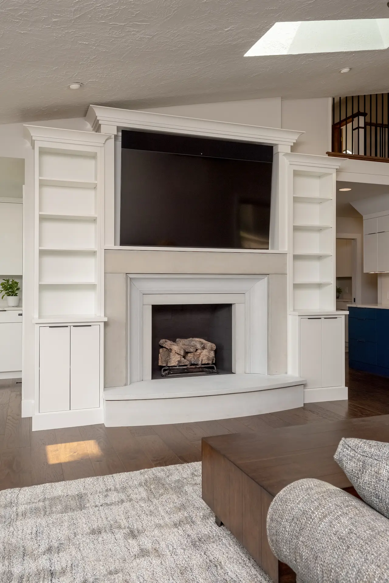 White custom fireplace built-ins with TV niche, open shelving, and living room cabinetry