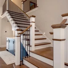 Custom wood staircase with white newel posts, dark handrails, and black iron balusters