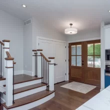 Entry staircase with wood treads, black balusters, and blue kitchen cabinetry