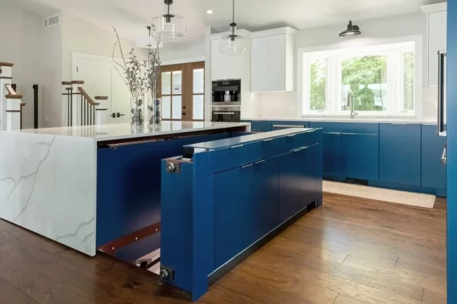 Custom blue kitchen island with concealed storage area and white quartz surround