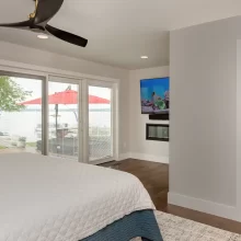Lakefront bedroom with sliding doors, fireplace wall, ensuite access, and Austin Lake views