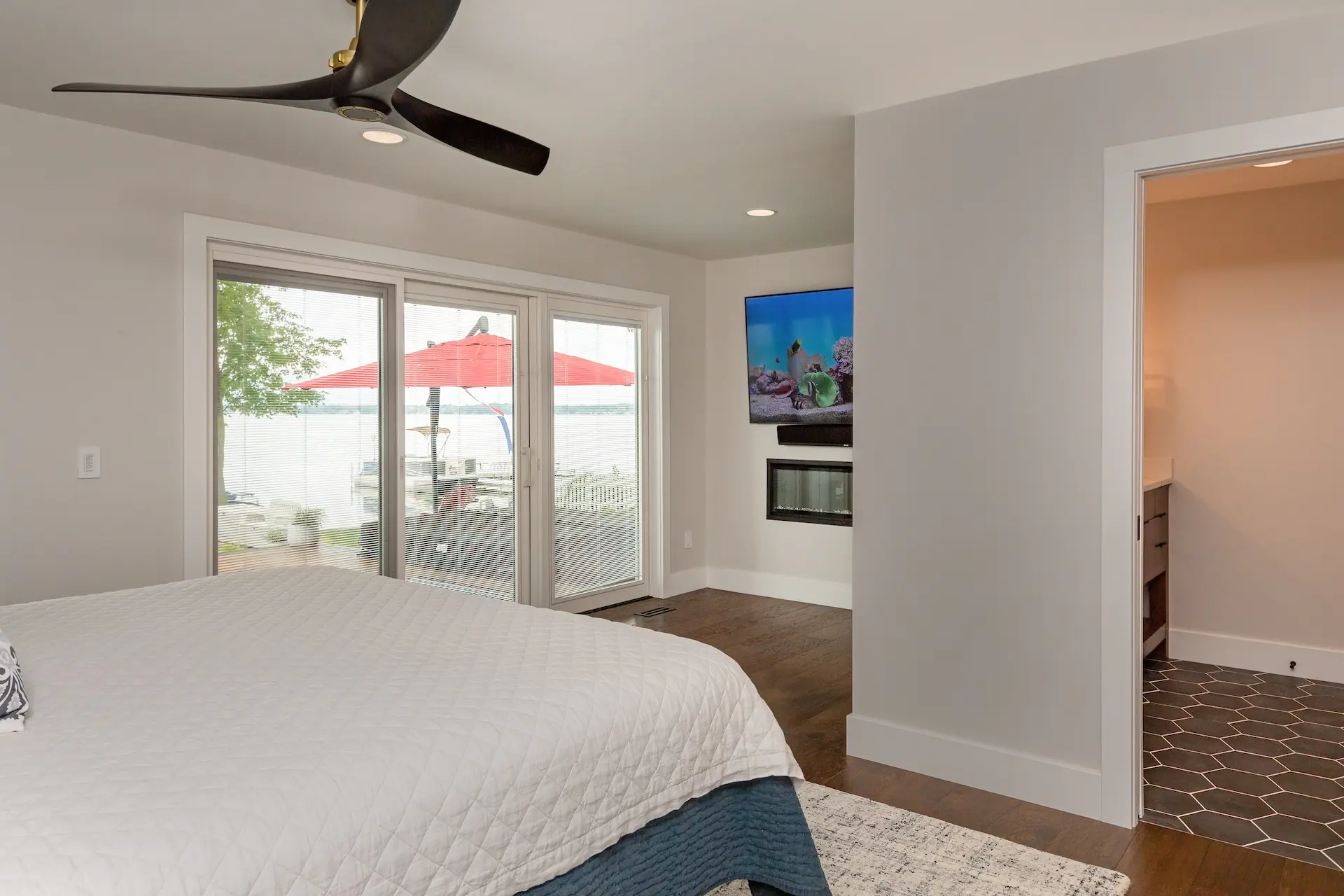Lakefront bedroom with sliding doors, fireplace wall, ensuite access, and Austin Lake views