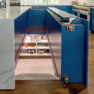 Close-up of hidden storage inside a blue kitchen island with white quartz countertop and custom cabinetry