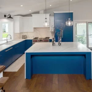 Open concept blue kitchen with white quartz island, professional range, and dining area