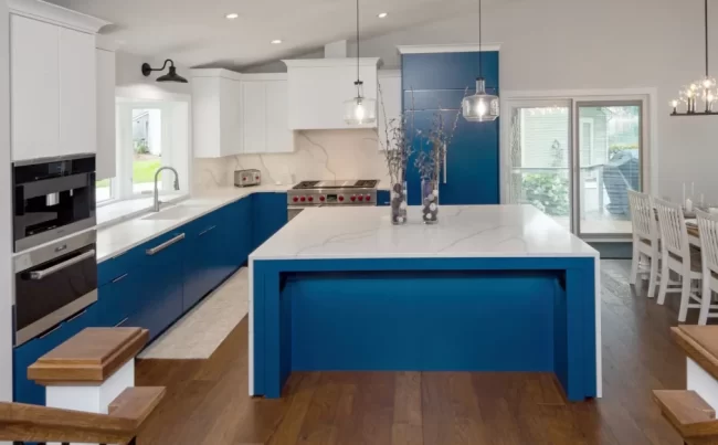 Open Concept Blue Kitchen | Pennings & Sons Open concept blue kitchen with white quartz island, professional range, and dining area