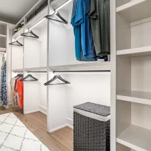 Walk-in closet with custom white shelving, hanging rods, accent lighting, and wood flooring