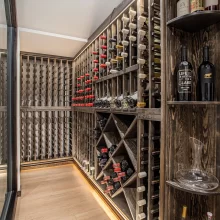 Custom wine cellar with dark wood bottle racks, glass enclosure, display shelving, and temperature control panel