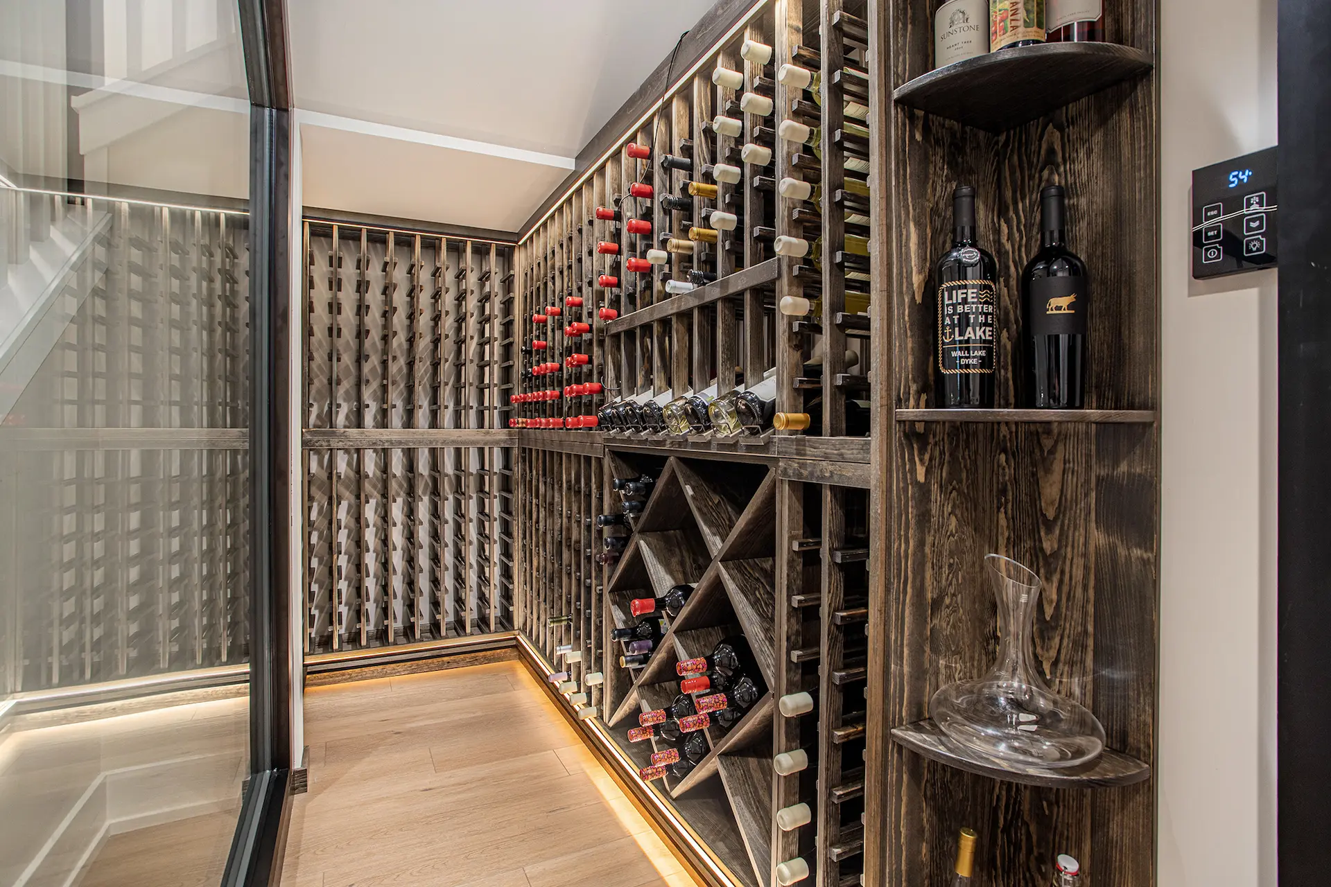 Custom wine cellar with dark wood bottle racks, glass enclosure, display shelving, and temperature control panel