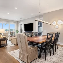 Dining room with wood table and lake view, connected to living room with sliding glass doors and lounge seating