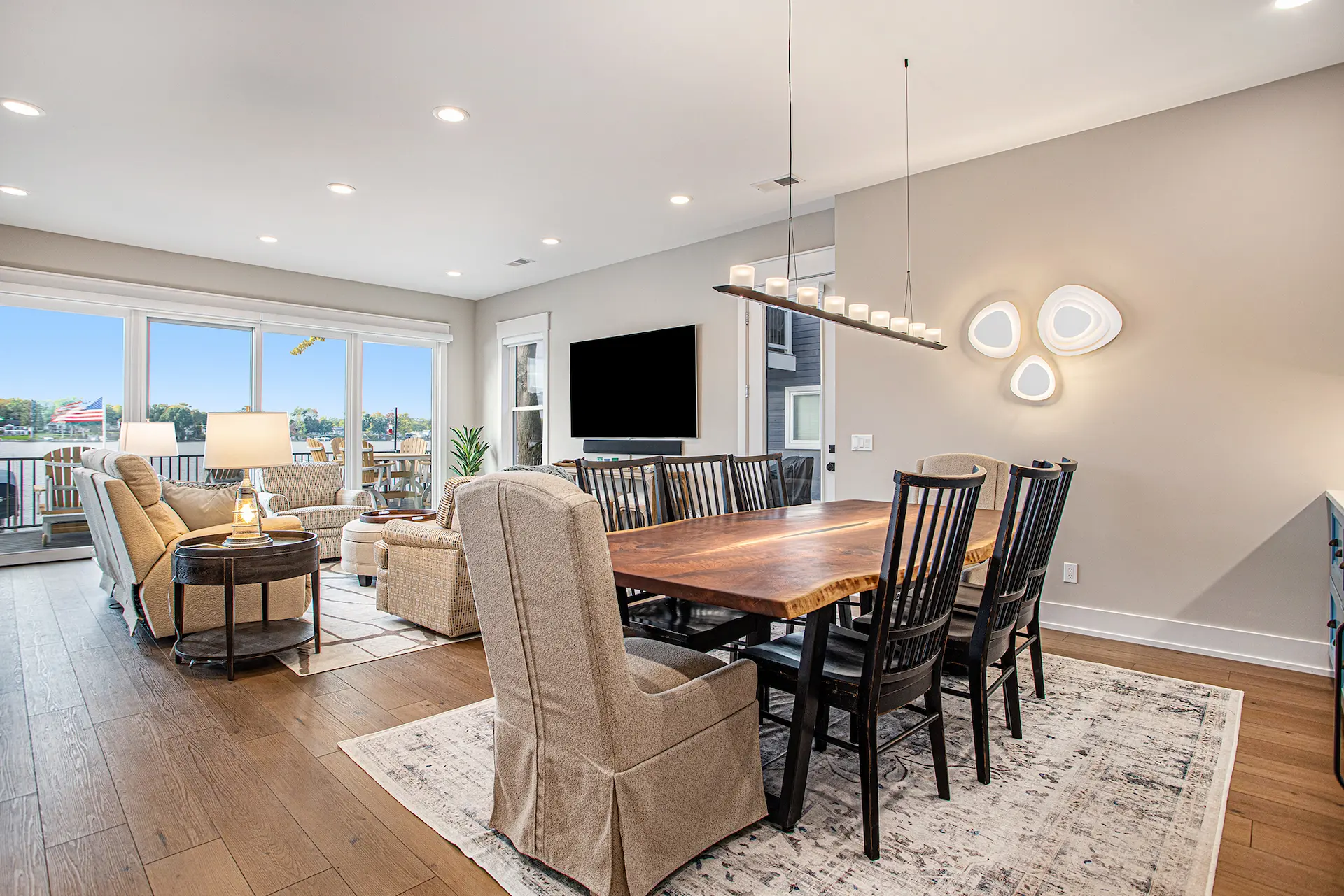 Dining room with wood table and lake view, connected to living room with sliding glass doors and lounge seating