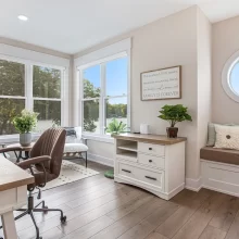 Bright home office with lake views, desk, sitting area, window seat, round window, and built-in storage
