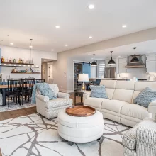 Open concept living room, dining area, kitchen, and blue beverage bar in a lakefront home